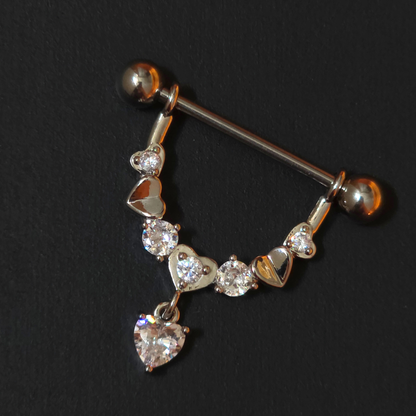 Nipple piercing ring with heart and diamond designs on a black background