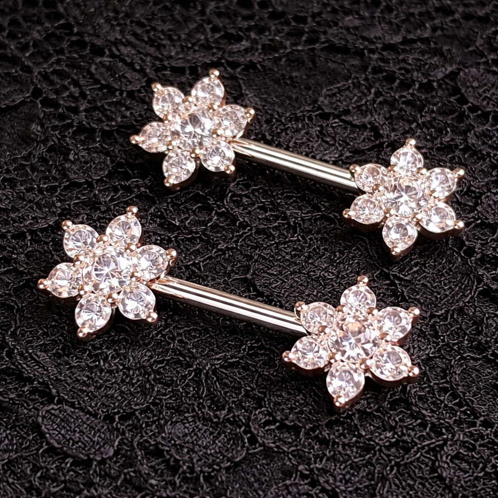 Pair of floral nipple bars with clear gemstones on a black textured background