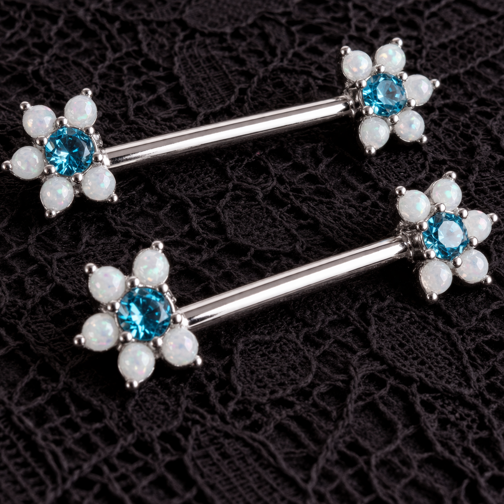 Pair of silver niple bars with blue gemstones and pearl-like stones on a black lace background