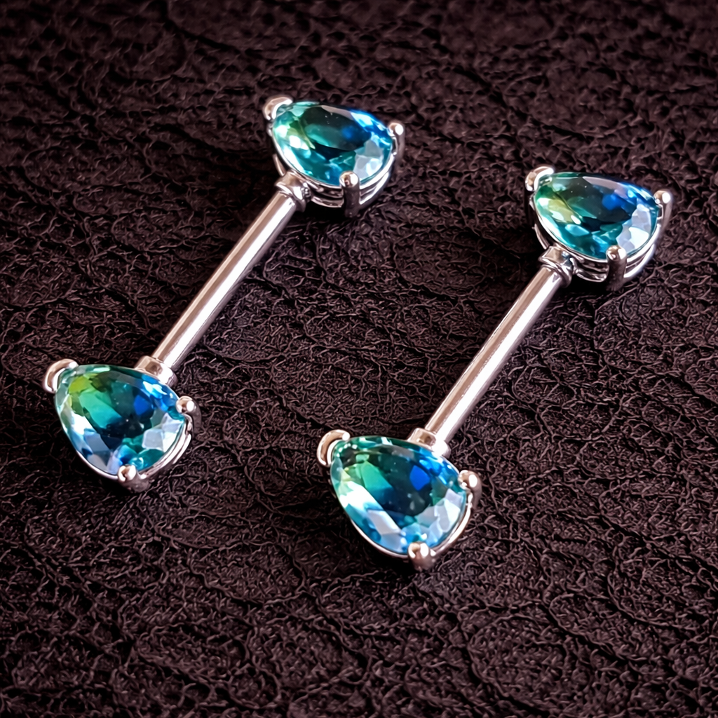Pair of silver nipple barbells with blue gemstones on a dark textured background