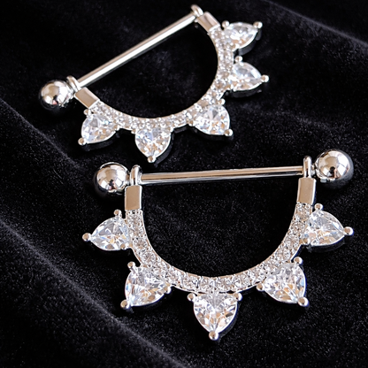 Pair of silver nipple bars with clear gemstones on a black background
