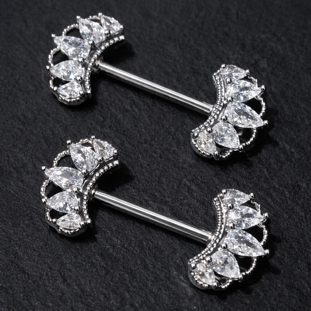 Pair of silver nipple bars with crown-like gemstones on a black background
