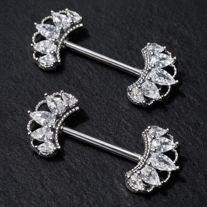 Pair of silver nipple bars with crown-like gemstones on a black background