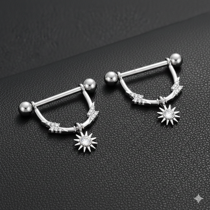 Pair of silver nipple bars with star-shaped charms on a black textured surface.