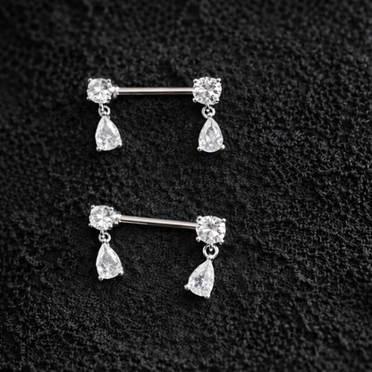 Pair of silver nipple bars with teardrop-shaped gemstones on a textured black background.