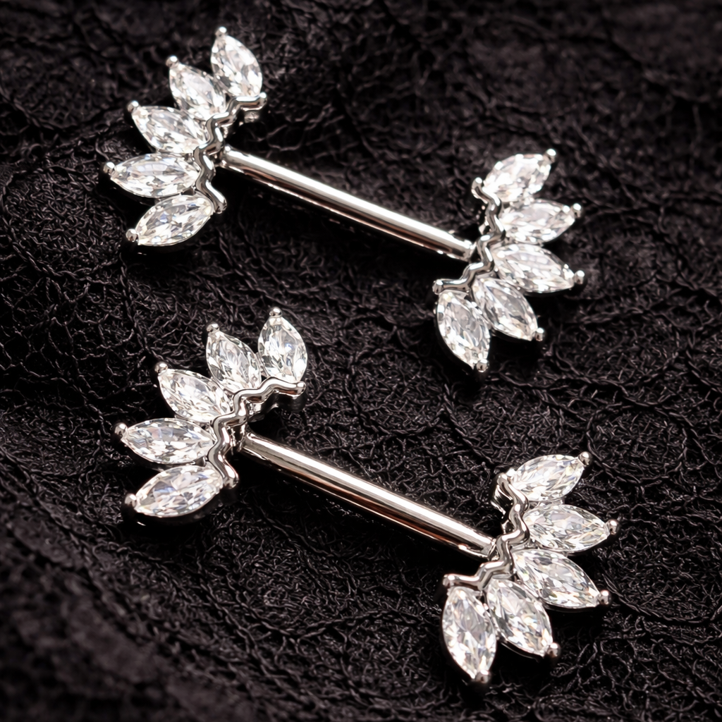 Pair of silver nipple piercing bars with crown design on a black textured background