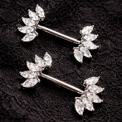 Pair of silver nipple piercing bars with crown design on a black textured background