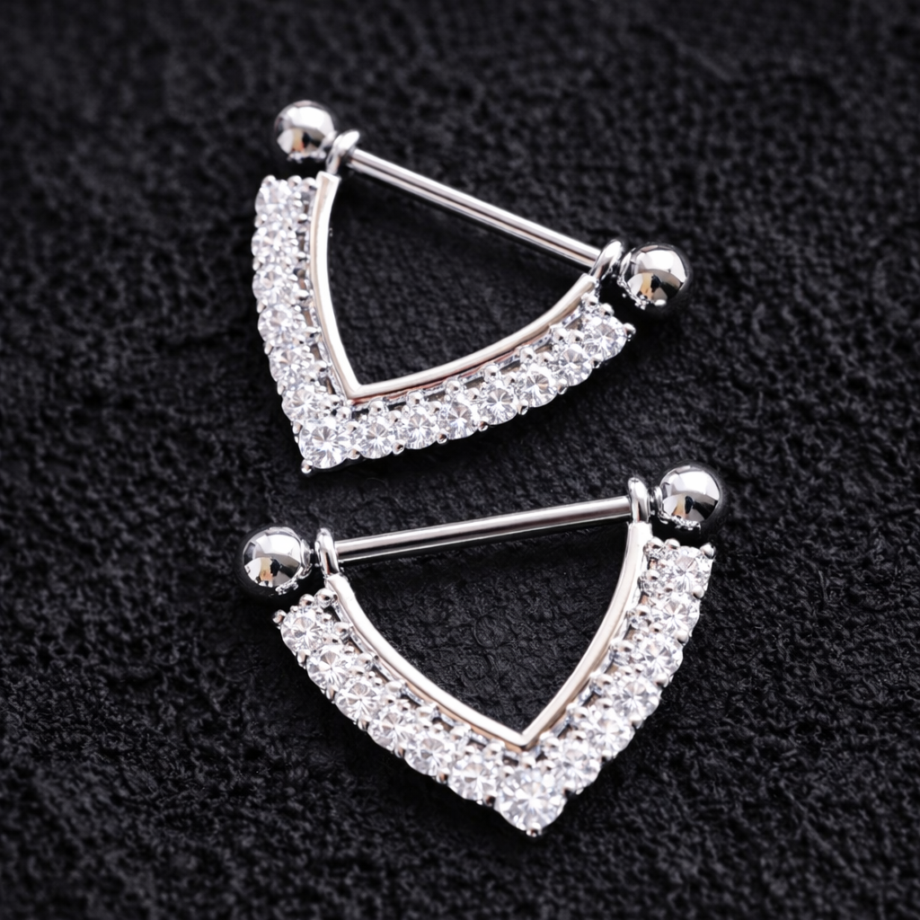 Pair of silver nipple shieldswith clear gemstones on a black background