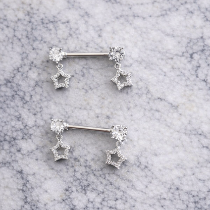 Pair of silver star-shaped nipple piercing bars on a marble surface