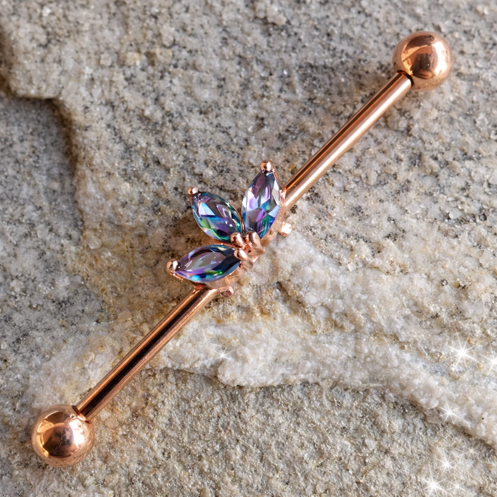 Rose gold barbell with multicolored gemstones on a textured stone surface