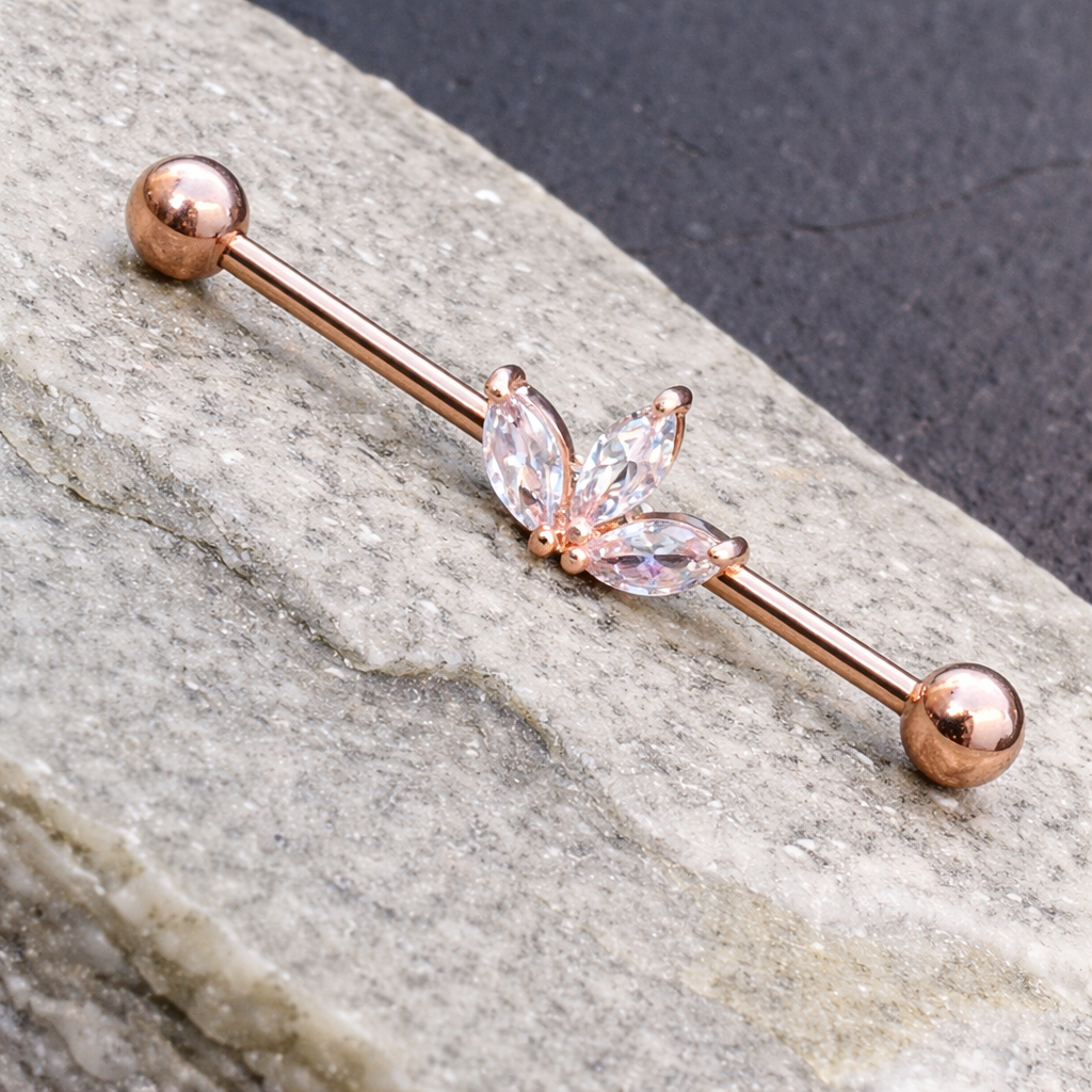 Rose gold ear ring with butterfly design on a stone surface
