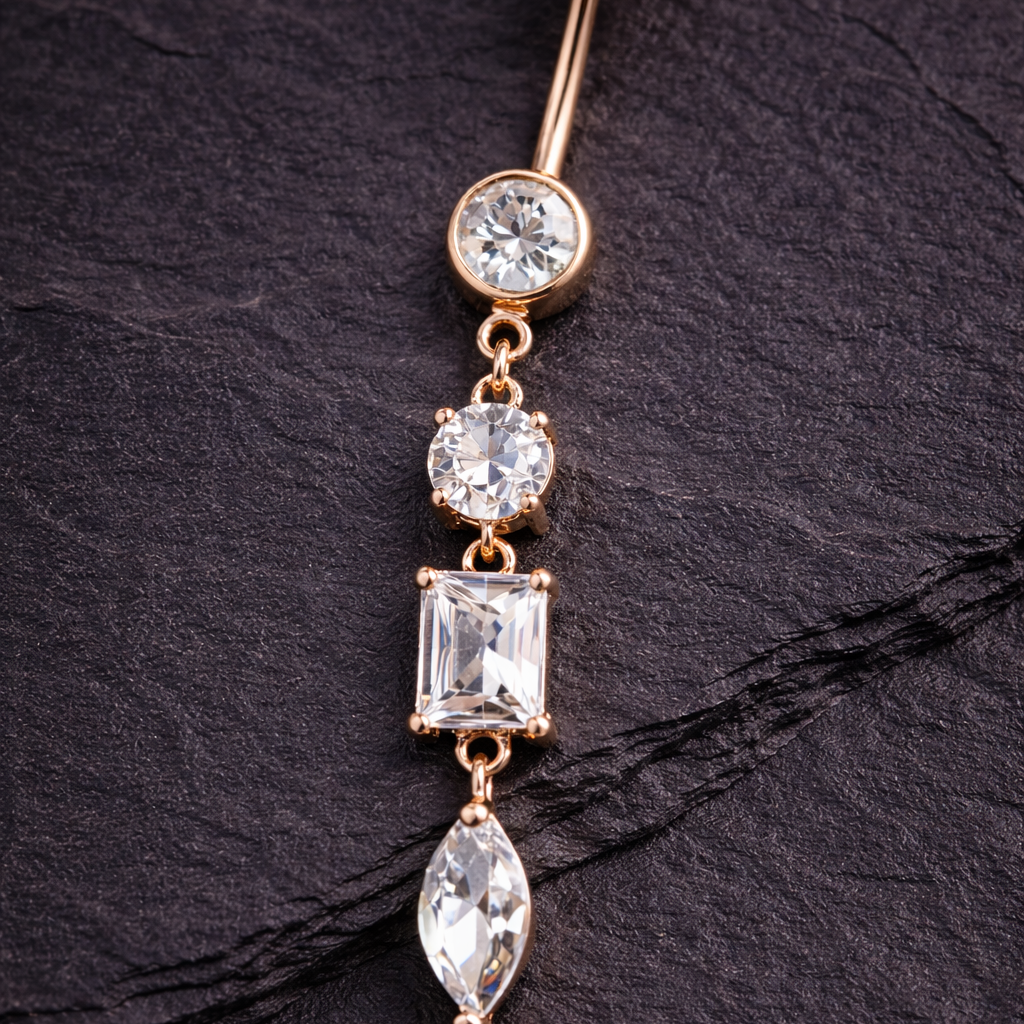 Rose gold belly button ring with clear gemstones on a dark surface