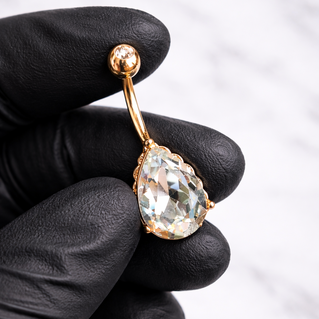 Navel bar with a large clear gemstone held by a gloved hand against a light background
