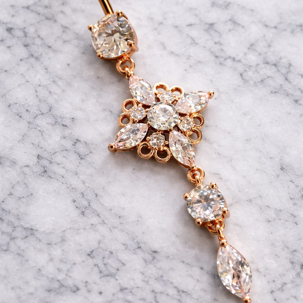 Rose gold belly button ring with clear gemstones on a marble background
