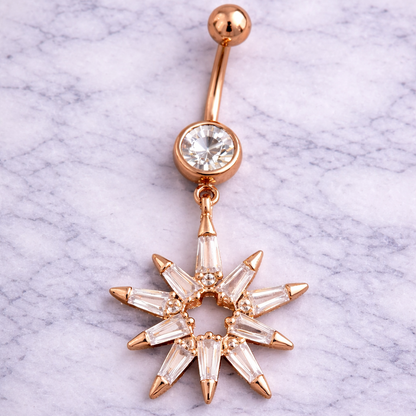 Rose gold belly button ring with star-shaped design on a marble background