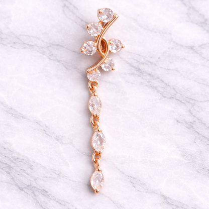 Rose gold belly ring with clear stones on a marble background