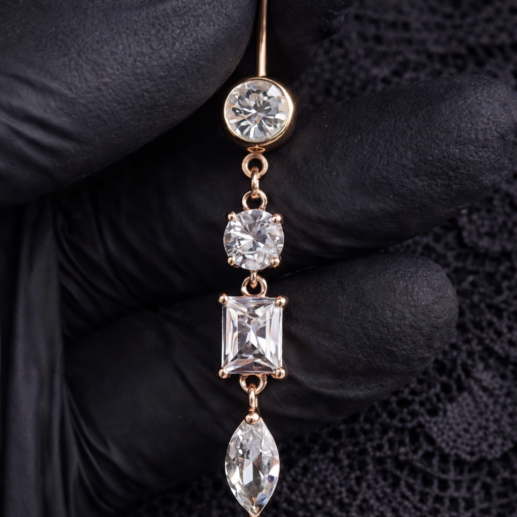 Rose Gold belly ring with clear gemstones held by a gloved hand on a dark background