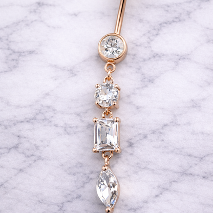 Rose gold belly button ring with clear gemstones on a marble background
