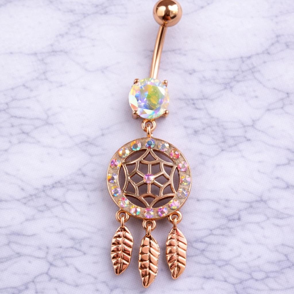 Gold belly button ring with dreamcatcher design on a marble background