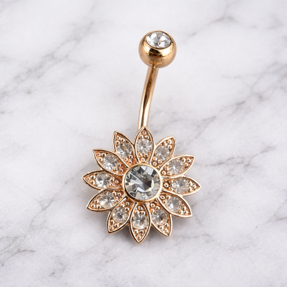 Rose gold belly button ring with floral design on a marble background