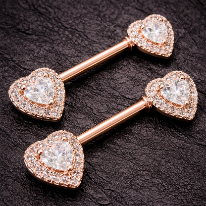 Rose gold heart-shaped nipple jewelry pieces on a dark textured background