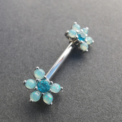 Stylish floral nipple piercing with a blue pearl center, CZ stones, and a 14G silver surgical steel barbell.