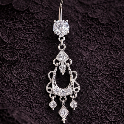 Silver belly button ring with chandelier design on a dark textured background