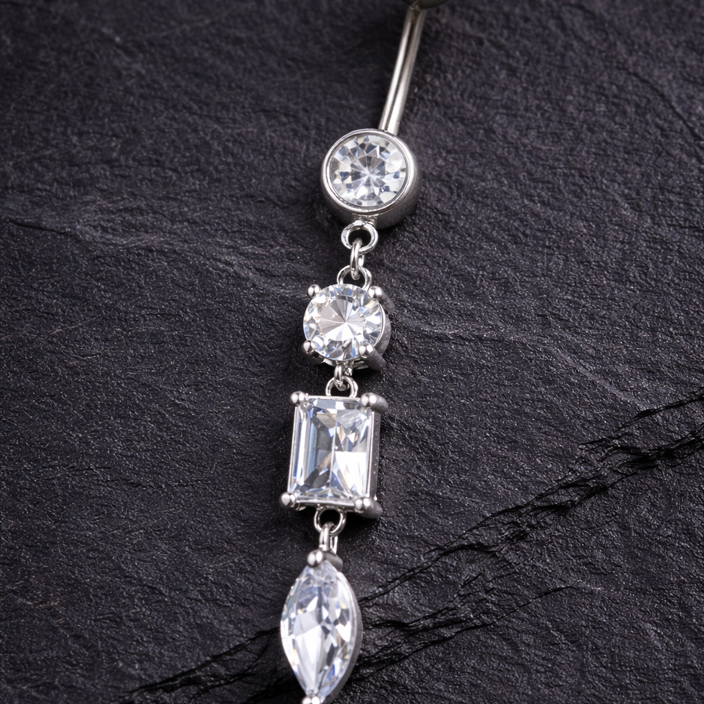 Belly button ring with clear gemstones on a black leather surface