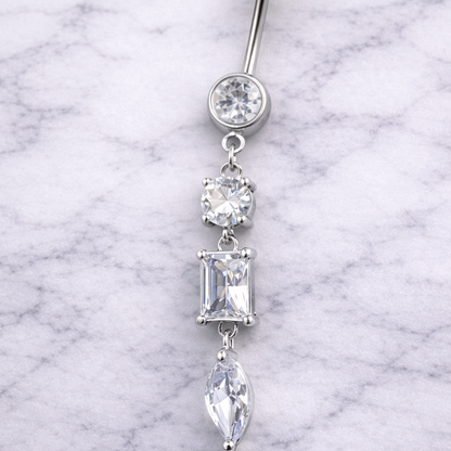 Silver belly button ring with clear gemstones on a marble background