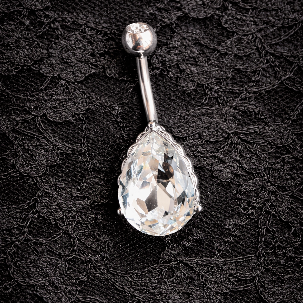 Belly button ring with teardrop crystal on a black lace background
