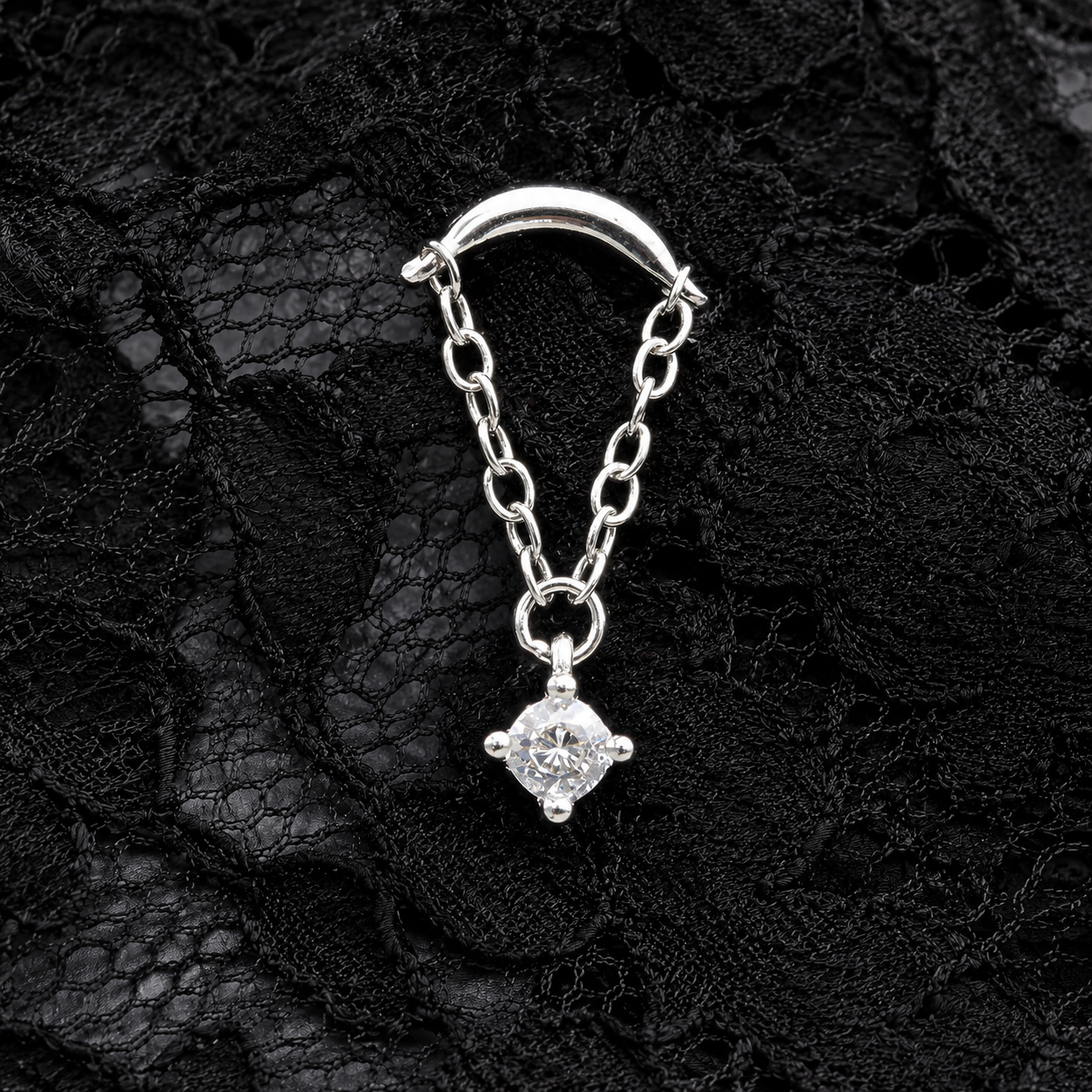 Silver chain with a diamond pendant on a black lace background