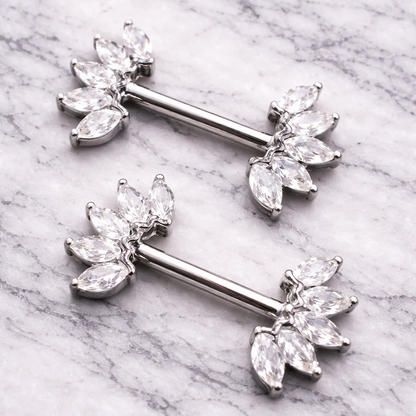 Silver crown nipple bars with clear gemstones on a marble background
