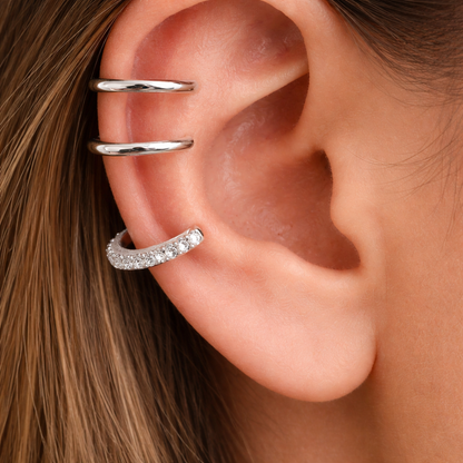 Close-up of an ear with silver ear cuff and earrings