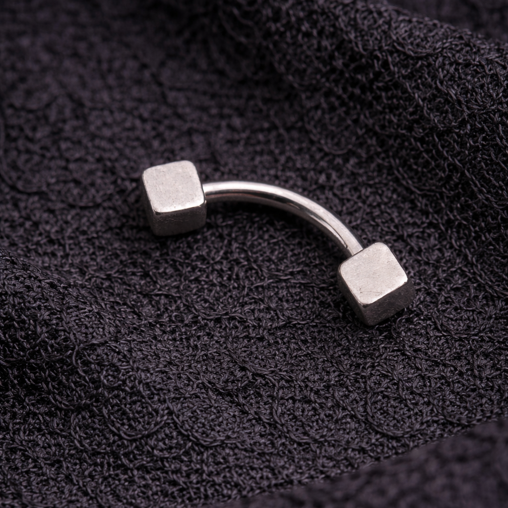 Silver curved eyebrow/rook earring on a textured black fabric background