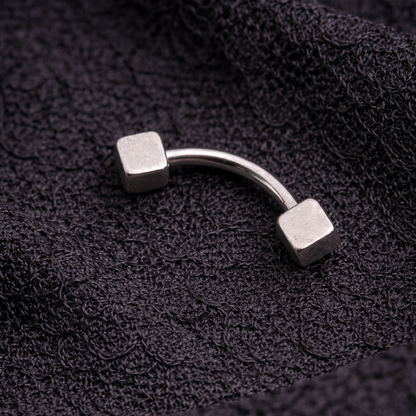 Silver curved eyebrow/rook earring on a textured black fabric background