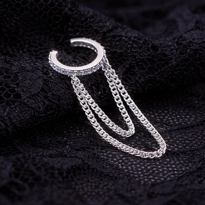 Silver earring with chain on a black textured background