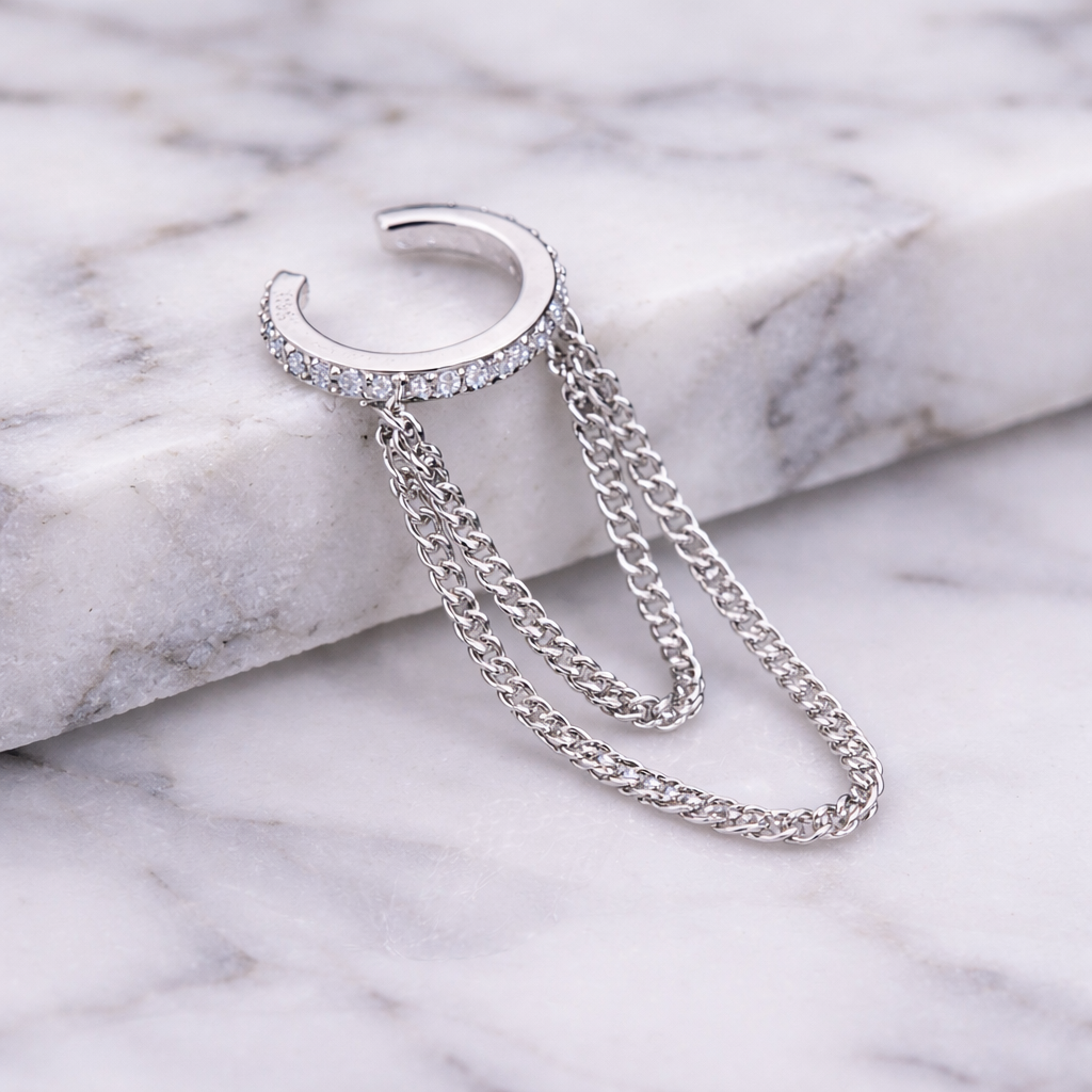 Silver hoop earring with a chain on a marble surface