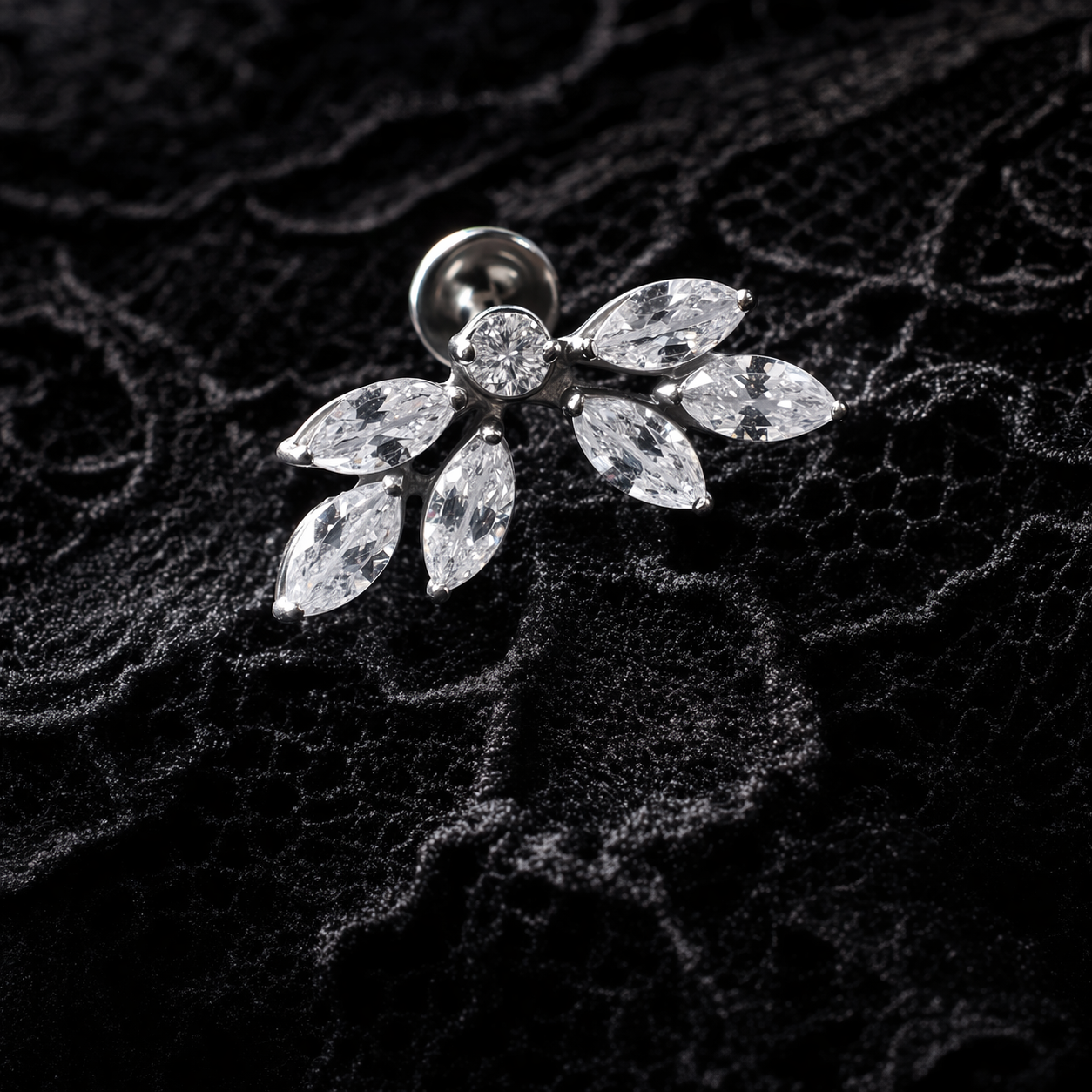 Silver earring with clear gemstones on a textured black background