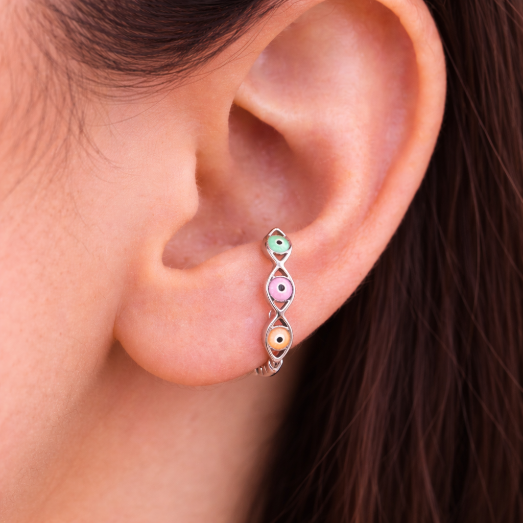 Close-up of an ear wearing a colorful earring with a blurred background