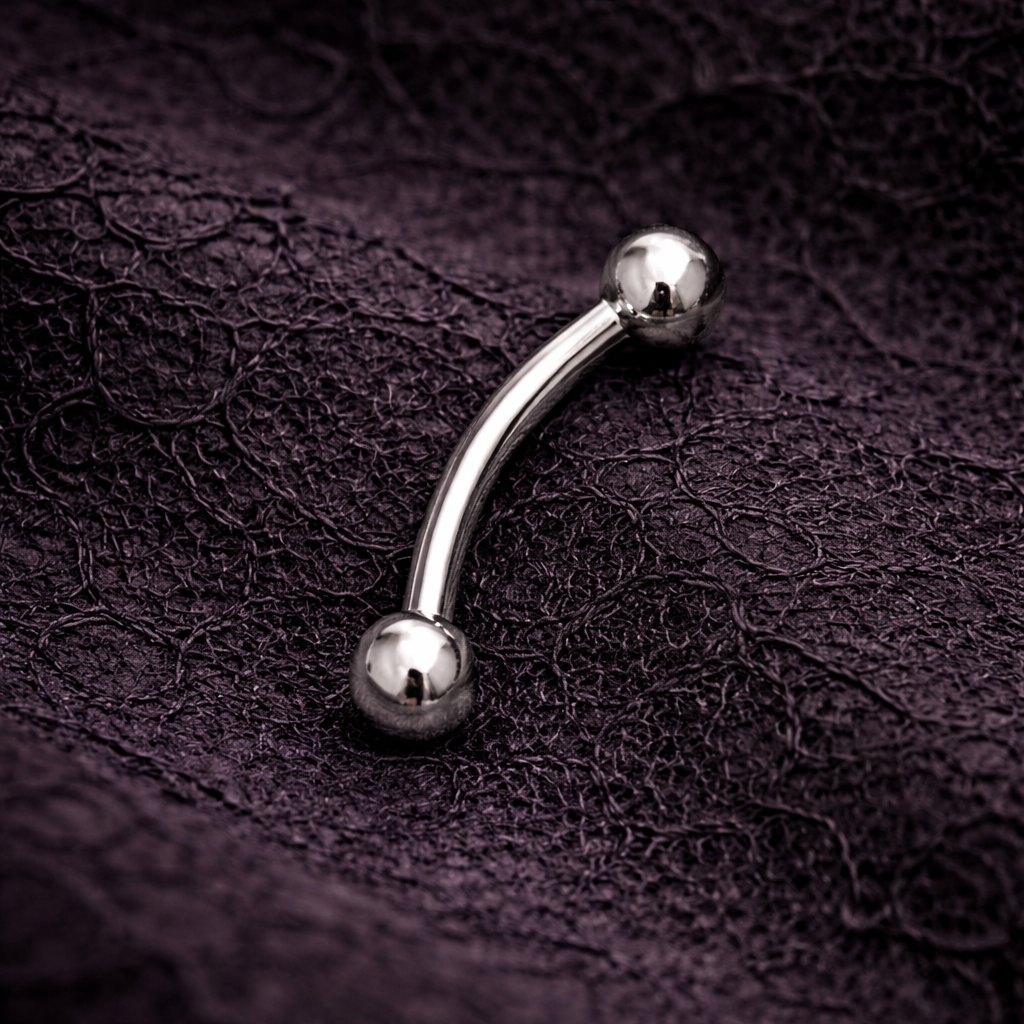 Silver eyebrow/eook bar on a dark textured surface