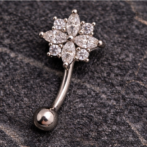 Silver eyebrow/rook bar with floral design on a textured dark surface