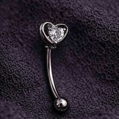 Silver eyebrow/rook bar with heart-shaped gem on a dark textured fabric background