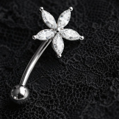 Silver eyebrow/rook barbell with a star-shaped gemstone on a black textured background