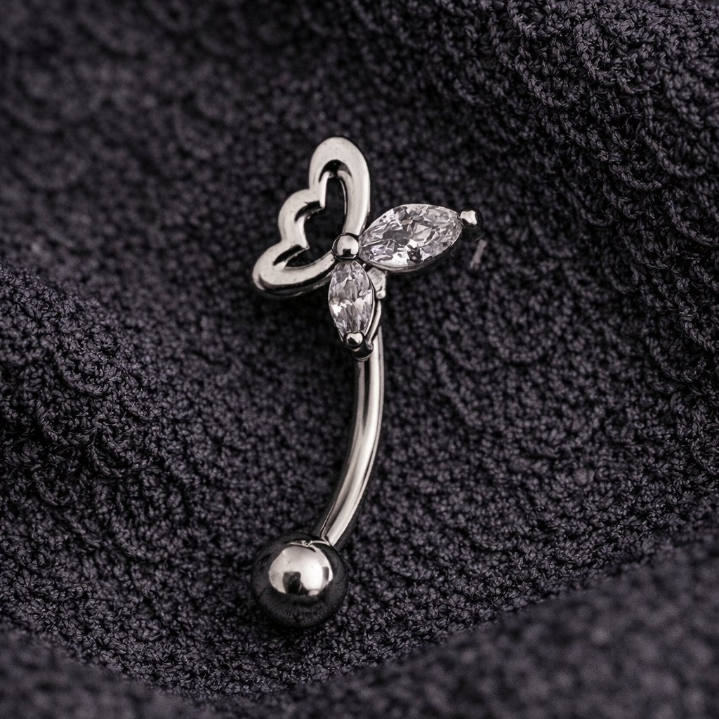 Silver eyebrow/rook barbell with butterfly design on a black textured background