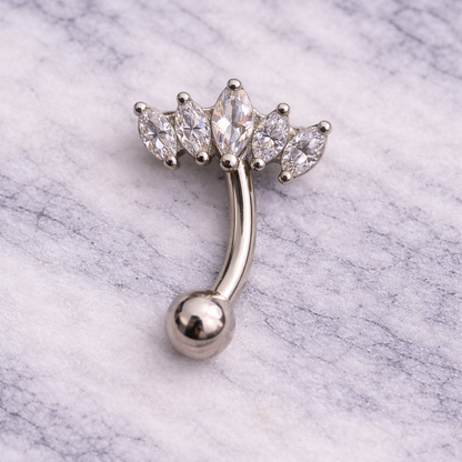 Silver eyebrow/rook ring with clear gemstones on a marble background