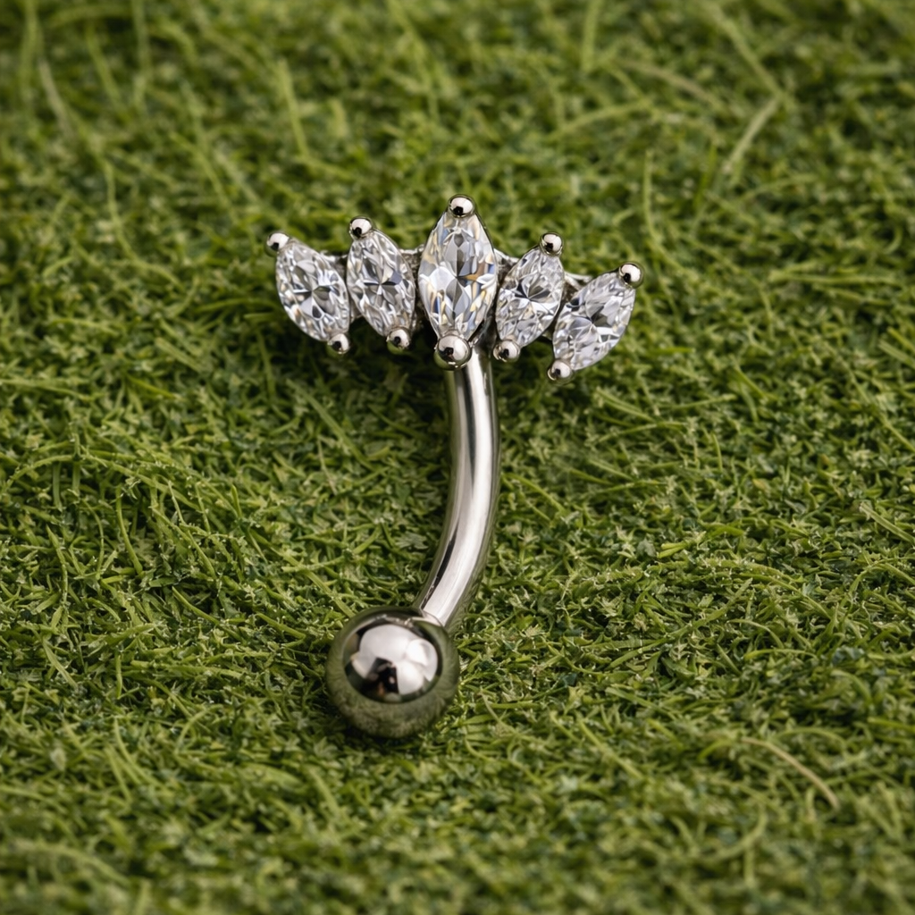 Silver eyebrow/rook ring with crown gemstones on a green textured background
