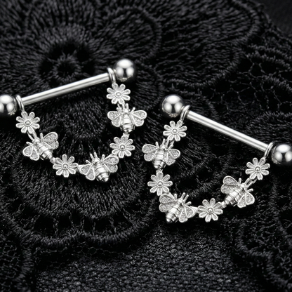 Silver floral nipple bars with bees charms on a black lace background