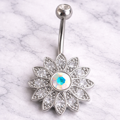 Silver belly button ring with a floral design and gemstone on a marble background