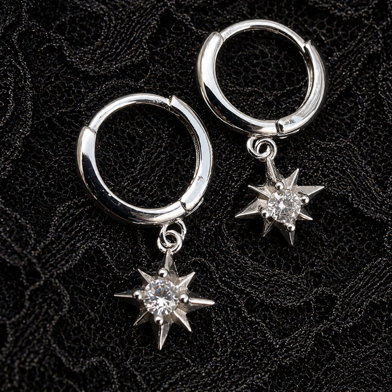Silver hoop earrings with star-shaped charms on a black textured background