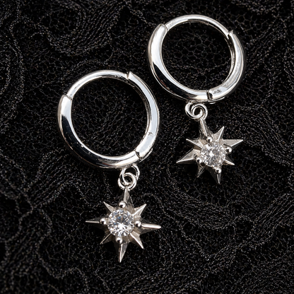 Silver hoop earrings with star-shaped charms on a black textured background